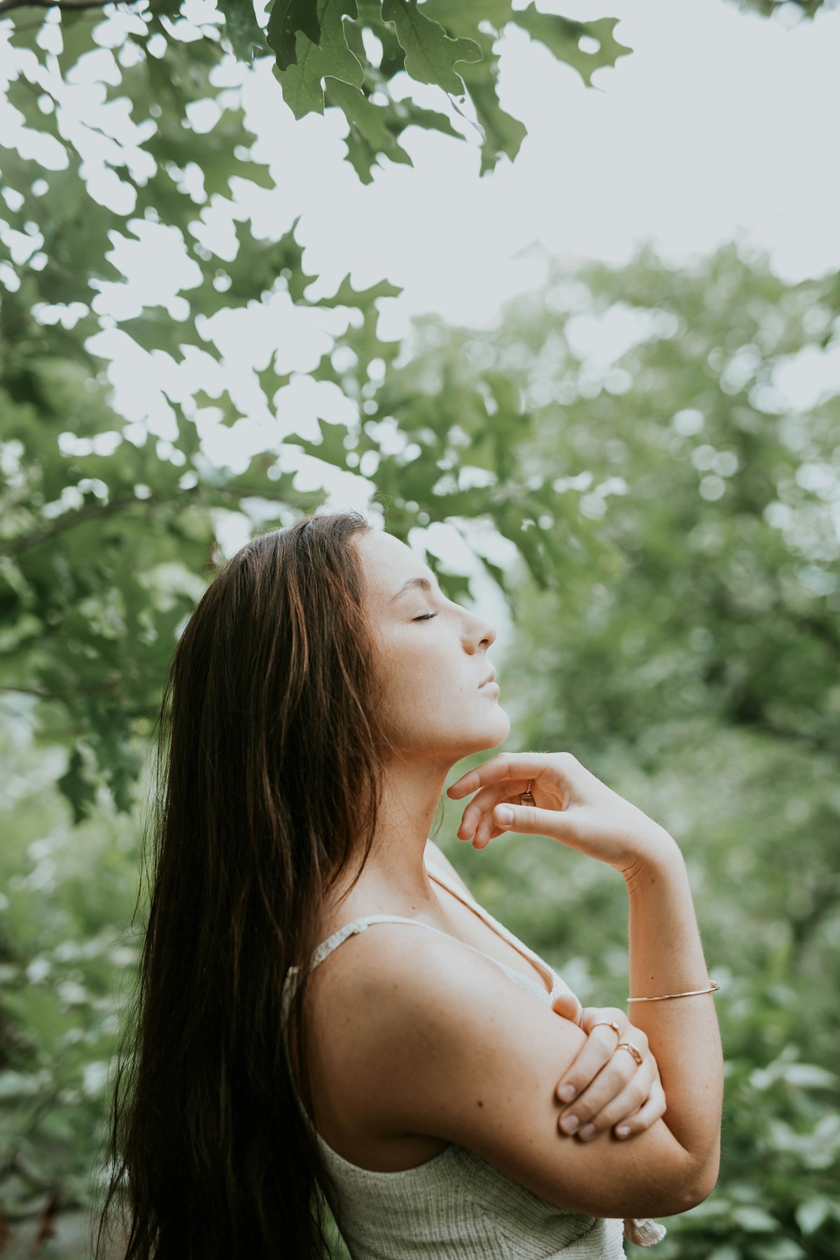 Mujer con los ojos cerrados y el rostro hacia la luz, respirando con calma entre el follaje